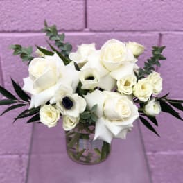 White roses and calla lilies in a clear glass vase