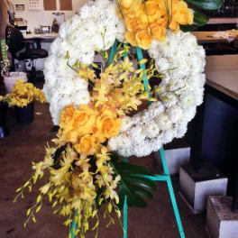 Large floral wreath with yellow roses and white blooms on a stand