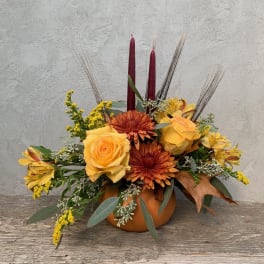 Autumn floral arrangement in a pumpkin vase with yellow roses and orange mums