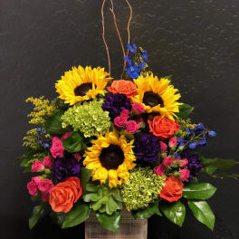 Colorful flower arrangement with sunflowers, roses, and hydrangeas in a wooden box