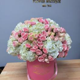Pink roses and white hydrangeas in a pink hat box with ribbon