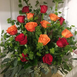 Bouquet of red and orange roses with greenery in a vase