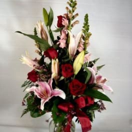 Tall bouquet of red roses and pink lilies in a glass vase