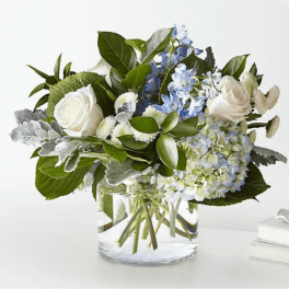White roses and blue hydrangea in a clear glass vase
