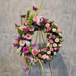 Large floral wreath with pink and lavender flowers on a black stand