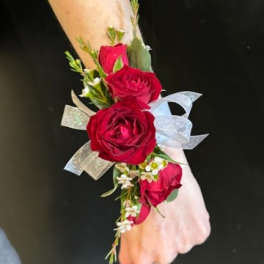 Red rose wrist corsage with ribbon on a wrist