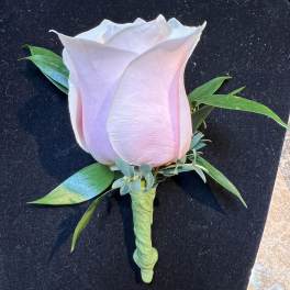 Single pale pink rose boutonniere with green leaves