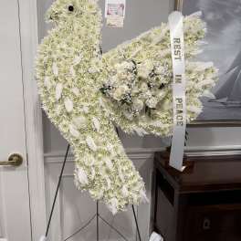 White floral peace sign funeral spray with a ribbon and roses