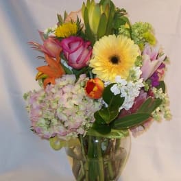 Mixed bouquet in a clear glass vase with pink, yellow, and orange blooms