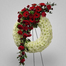 Red flowers arranged on a white funeral wreath on an easel