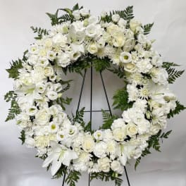 White floral funeral wreath on a black stand