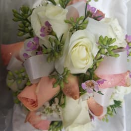 Small bouquet of white and blush roses with purple accents and ribbon
