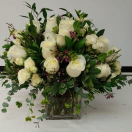 White rose bouquet in a clear glass vase with mixed greenery
