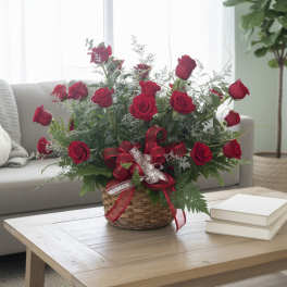 Basket arrangement of red roses with ribbon on a coffee table