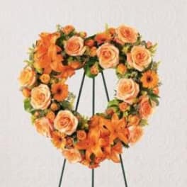 Orange rose and lily wreath on a black stand