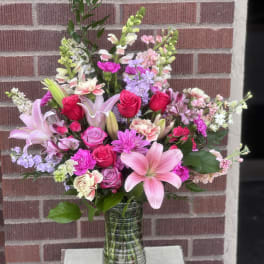 Mixed pink bouquet with roses, lilies, and snapdragons in a glass vase