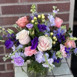 Mixed pink, purple, and lavender flowers in a glass vase