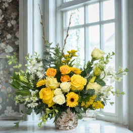 Yellow and white floral arrangement in a floral-print vase