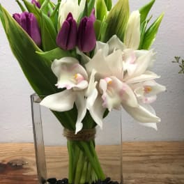 Purple tulips and white orchids in a clear glass vase