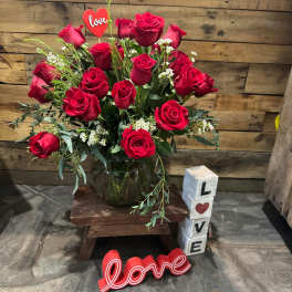 Red roses in a glass vase with love-themed decorations