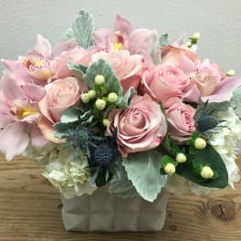 Pink roses and orchids arranged in a white vase