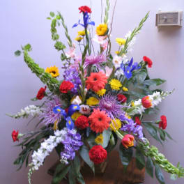 Tall mixed flower arrangement with bright red, yellow, blue, and purple blooms