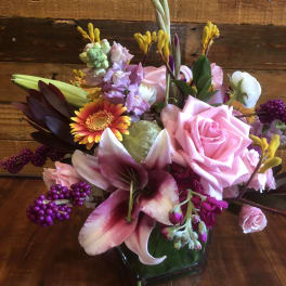 Pink roses and lilies in a glass vase with purple accents