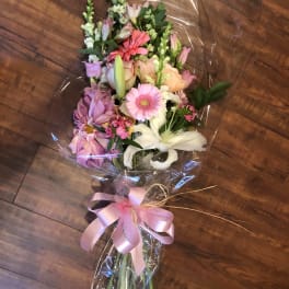 Mixed bouquet with pink, white, and peach flowers wrapped in clear plastic