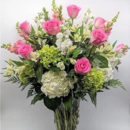 Bouquet of pink roses, white hydrangeas, and white flowers in a clear vase
