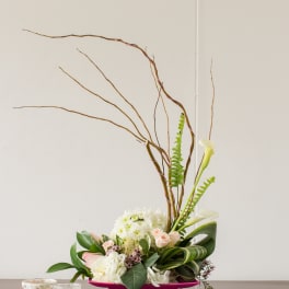 Modern floral arrangement in a pink container with white and blush blooms