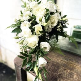 White rose bouquet with greenery on a wooden table