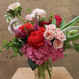 Mixed bouquet of red, pink, and white flowers in a glass vase