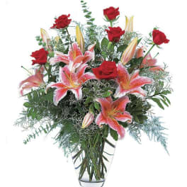 Red roses and pink lilies in a clear glass vase