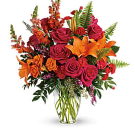 Bouquet of pink roses and orange lilies in a clear glass vase