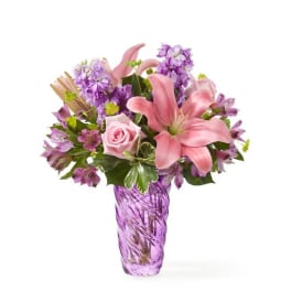 Pink lilies and purple flowers in a purple glass vase