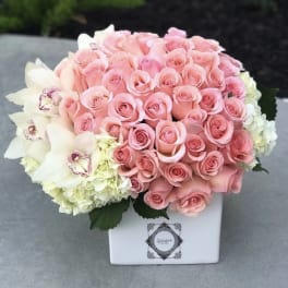 Pink roses and white orchids in a white square vase