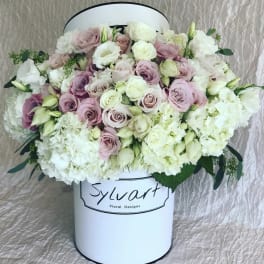 Pink and white roses arranged in a white hat box