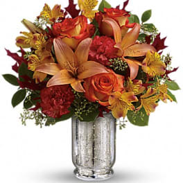 Autumn bouquet of orange roses and lilies in a silver vase