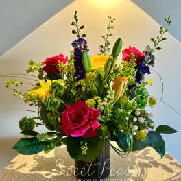 Mixed bouquet with pink roses, yellow daisies, and lilies in a vase