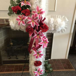 Standing floral cross with pink lilies, red carnations, and white ruffles