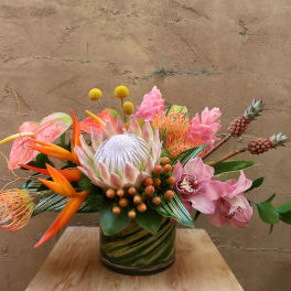 Tropical flower arrangement in a green glass vase with pink and orange blooms