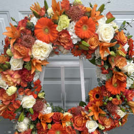 Orange and white floral wreath with roses and lilies