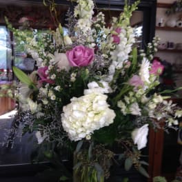 Tall mixed bouquet with pink roses and white blooms in a glass vase