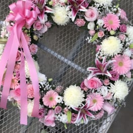 Pink and white floral wreath with a large pink ribbon bow