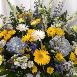 Mixed yellow, white, blue, and lavender flowers in a white basket