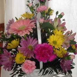 Mixed pink, yellow, and purple flowers in a white basket