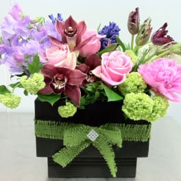 Mixed bouquet of pink roses, orchids, and purple flowers in a black box