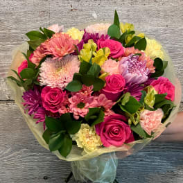 Bouquet of pink roses, chrysanthemums, and alstroemeria wrapped in pale paper