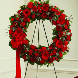 Red floral wreath on a black stand with a red ribbon