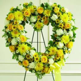 Heart-shaped floral wreath with yellow roses and white flowers on an easel